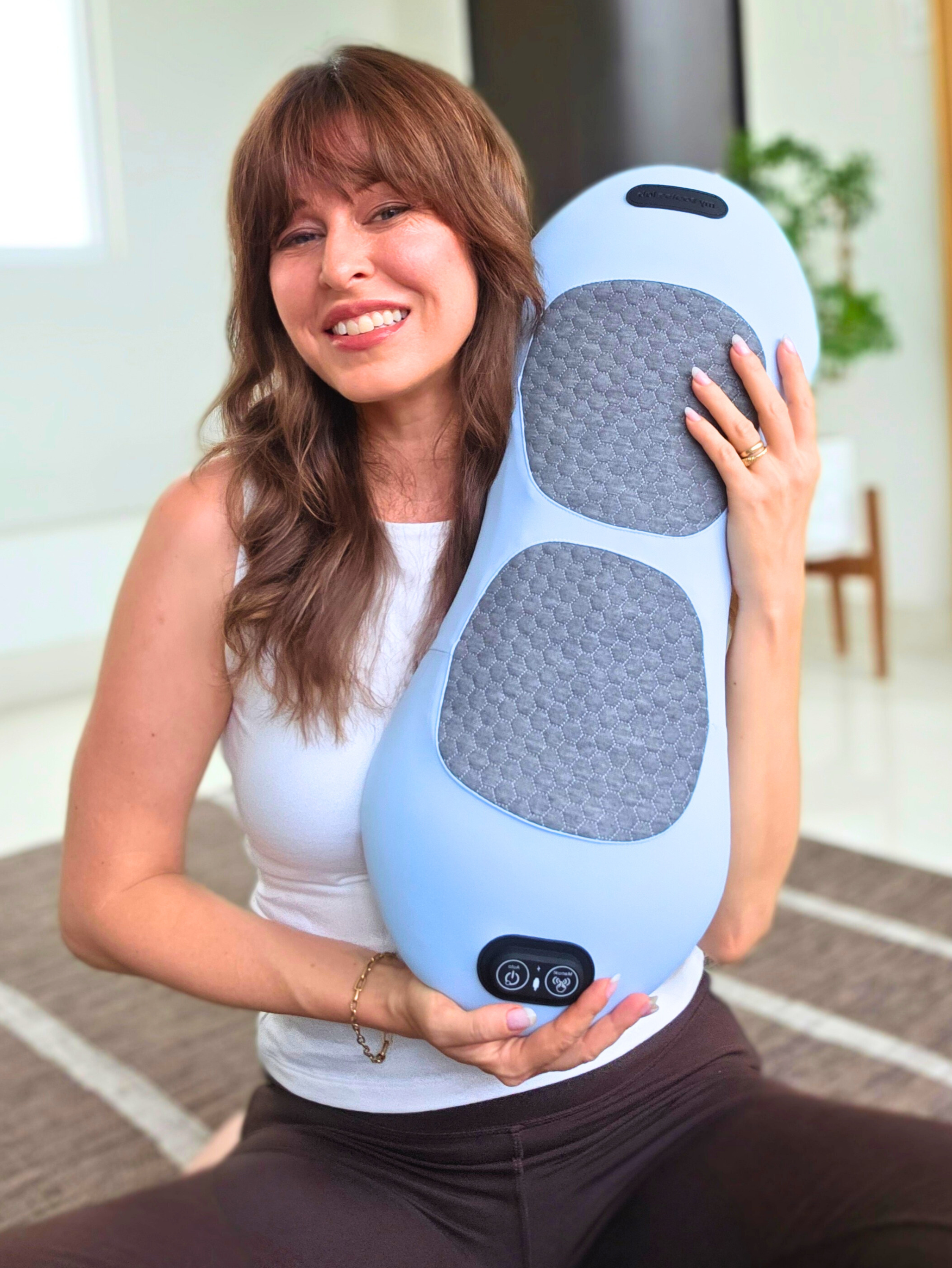 Woman holding the Cordia 3-in-1 Back Massager against her side, red-light glow visible on the pads